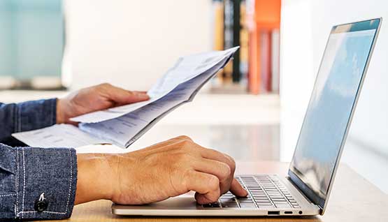 A client sits at their table making a bill payment online with their laptop.